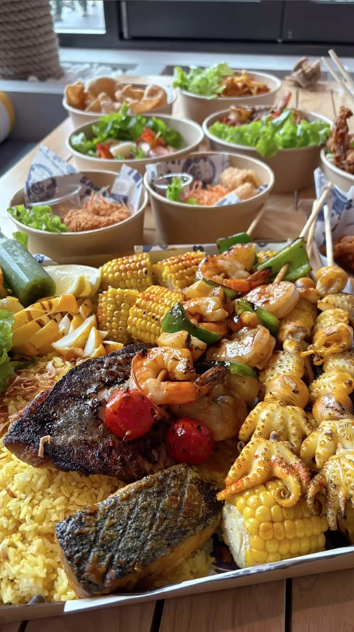 A grilled platter in the foreground and individual seafood dishes in the background