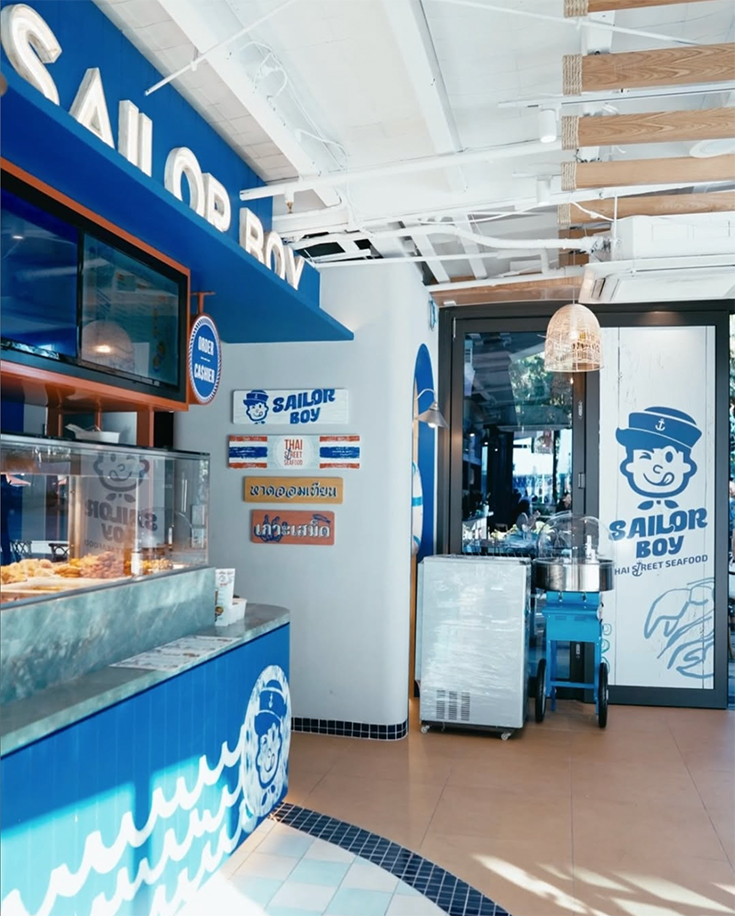 Blue and white Interior of Sailor Boy Thai restaurant featuring its counter and display of food.