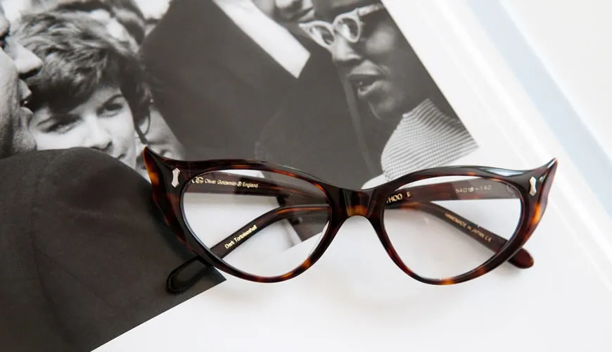 Tortoiseshell cat-eye glasses resting on black and white magazine photographs