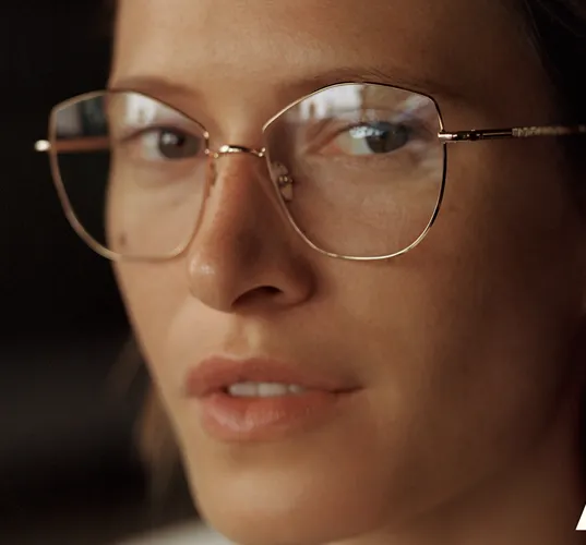 Close-up of a person wearing large, vintage-style metal-framed glasses