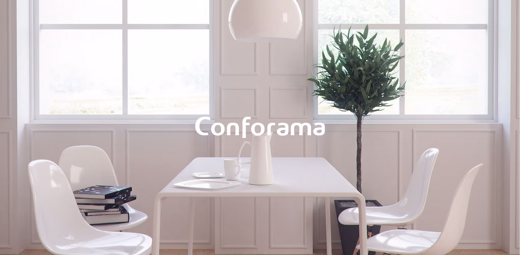 Minimalist dining room with white table, four white chairs, stacked books, a pitcher, cup, and a potted plant near large windows.