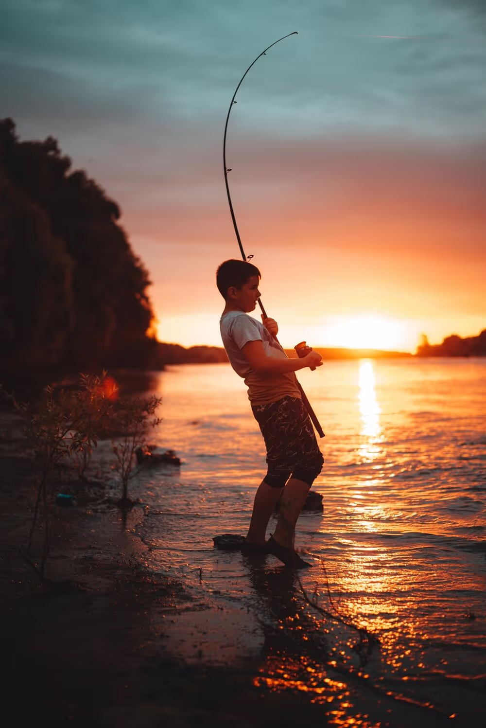 Jeune pecheur près du coucher de soleil