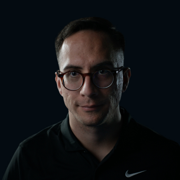 A man on the tennis court smiling into the camera