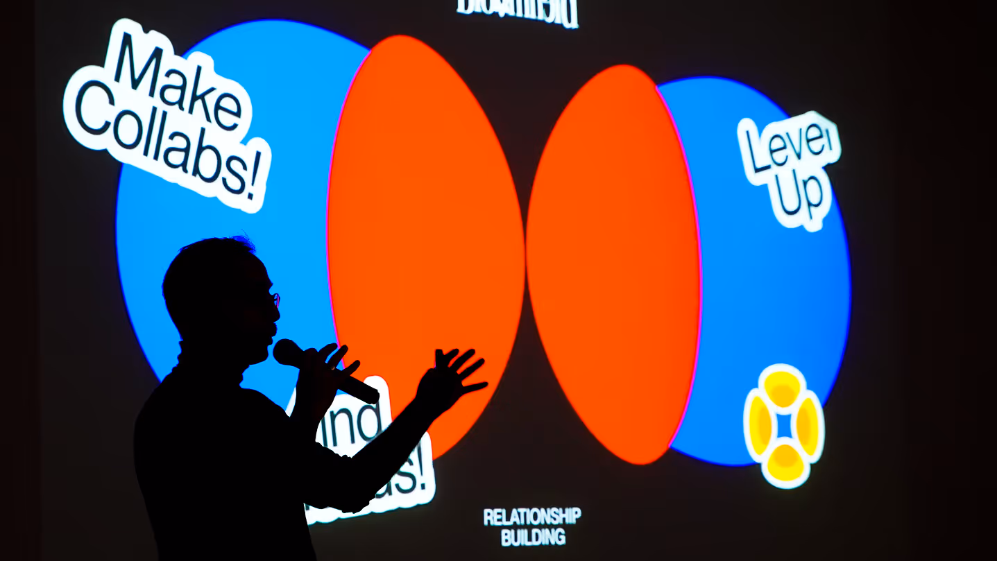 Silhouette of a person speaking with microphone in front of a colorful relationship building Venn diagram.
