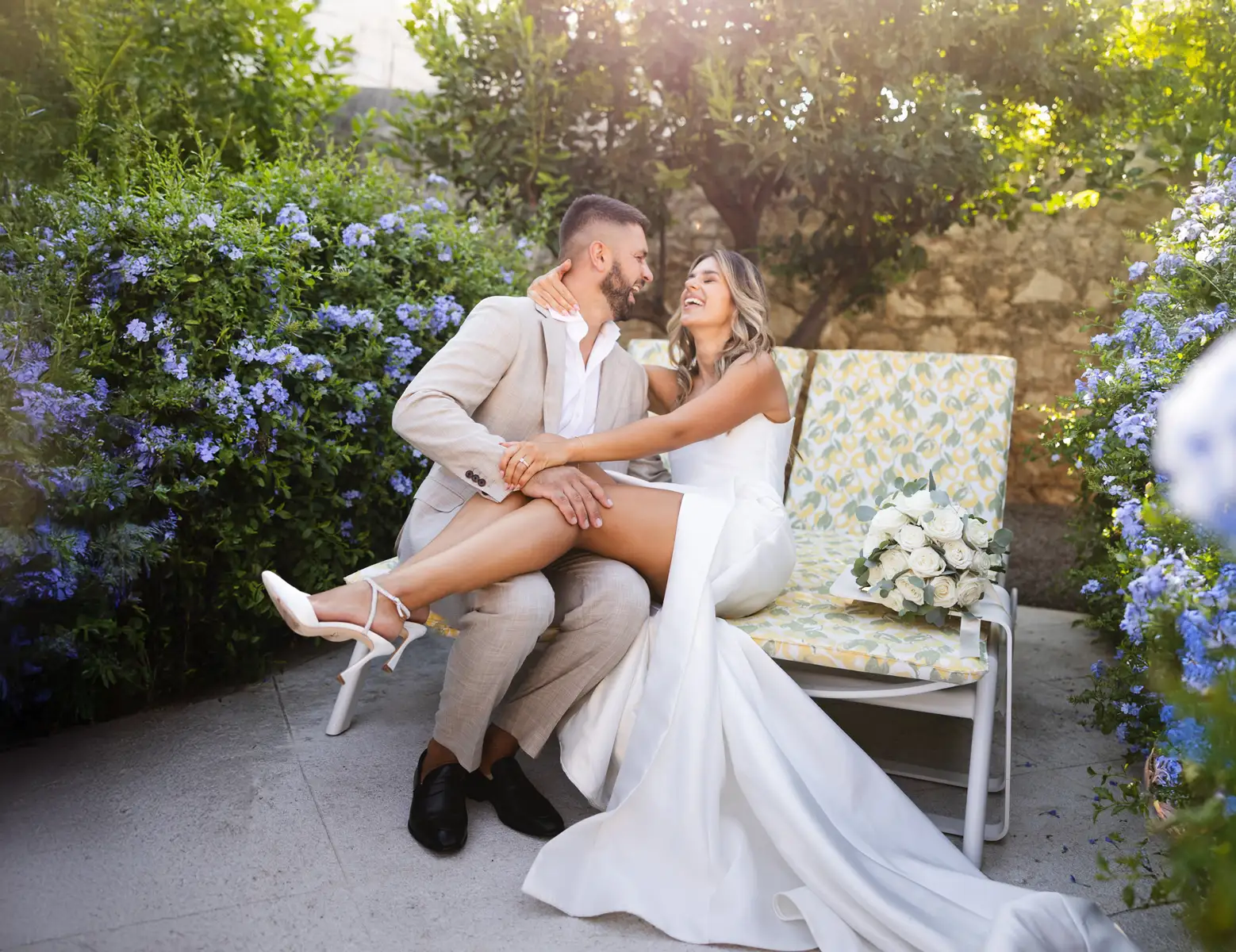 Bride and groom laughing together on a garden bench at Hotel Lemongarden, Brač.