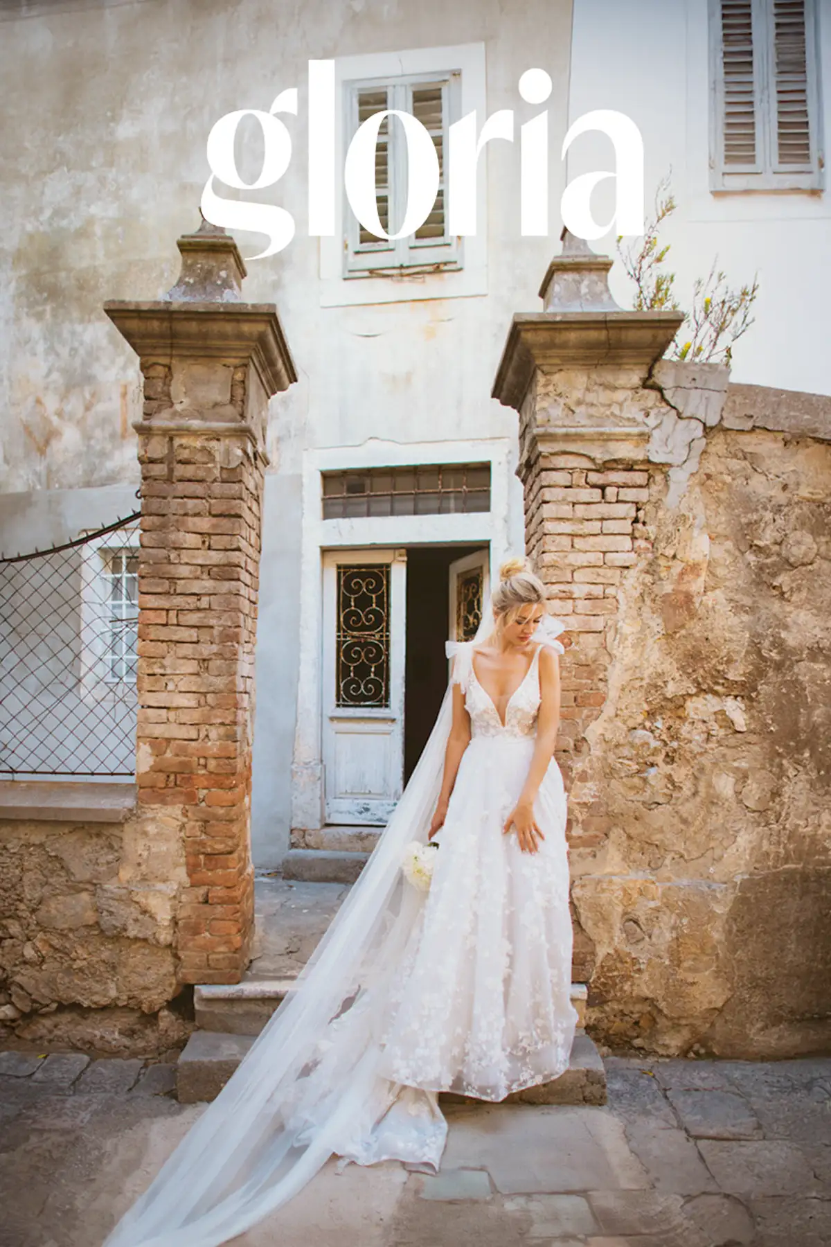 Bride standing alone in a stone gateway between brick pillars, weathered plaster building, Lošinj