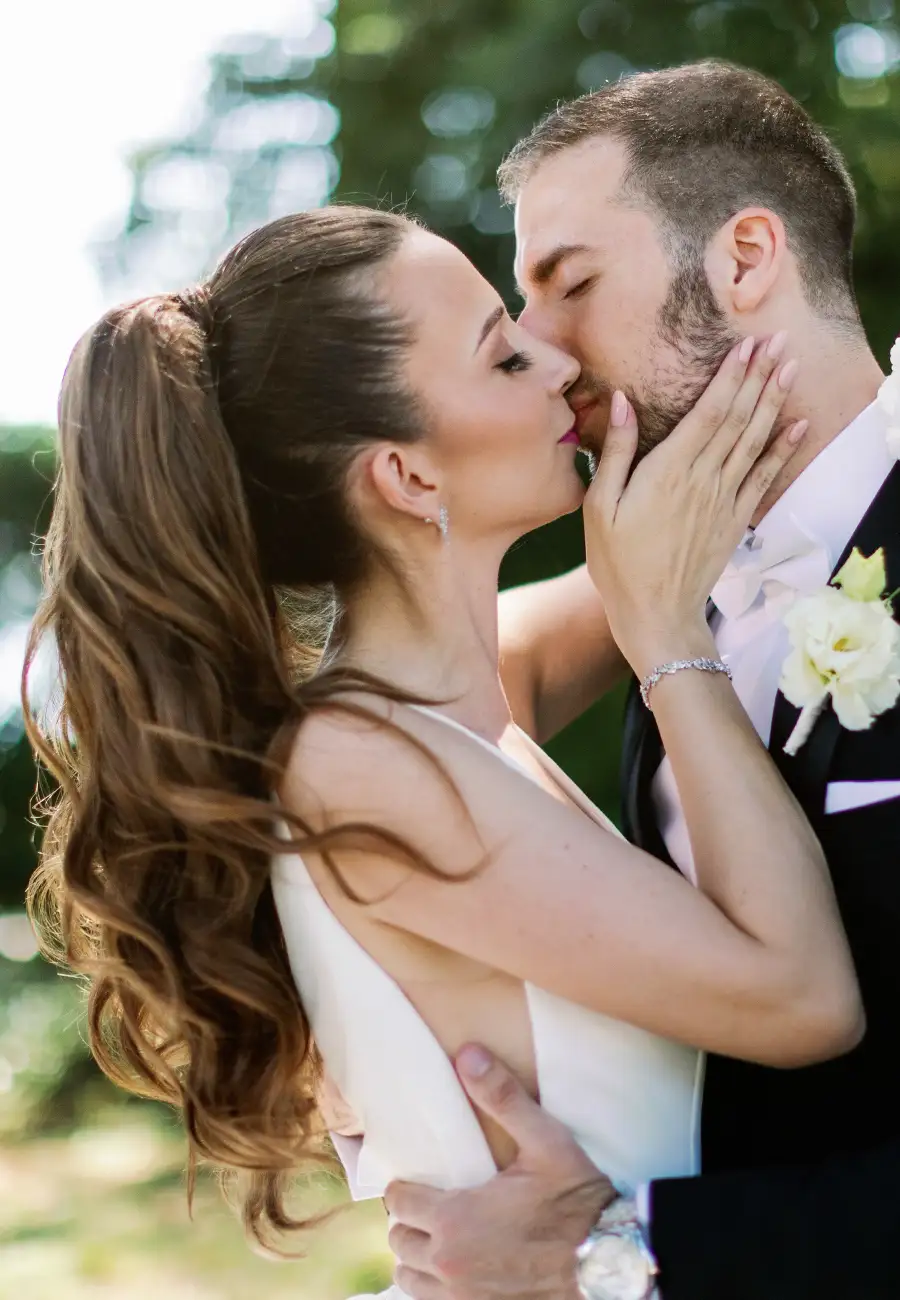 Eneja and Vedran embracing closely, her hand on his face, blurred green foliage behind, backlit, Opatija