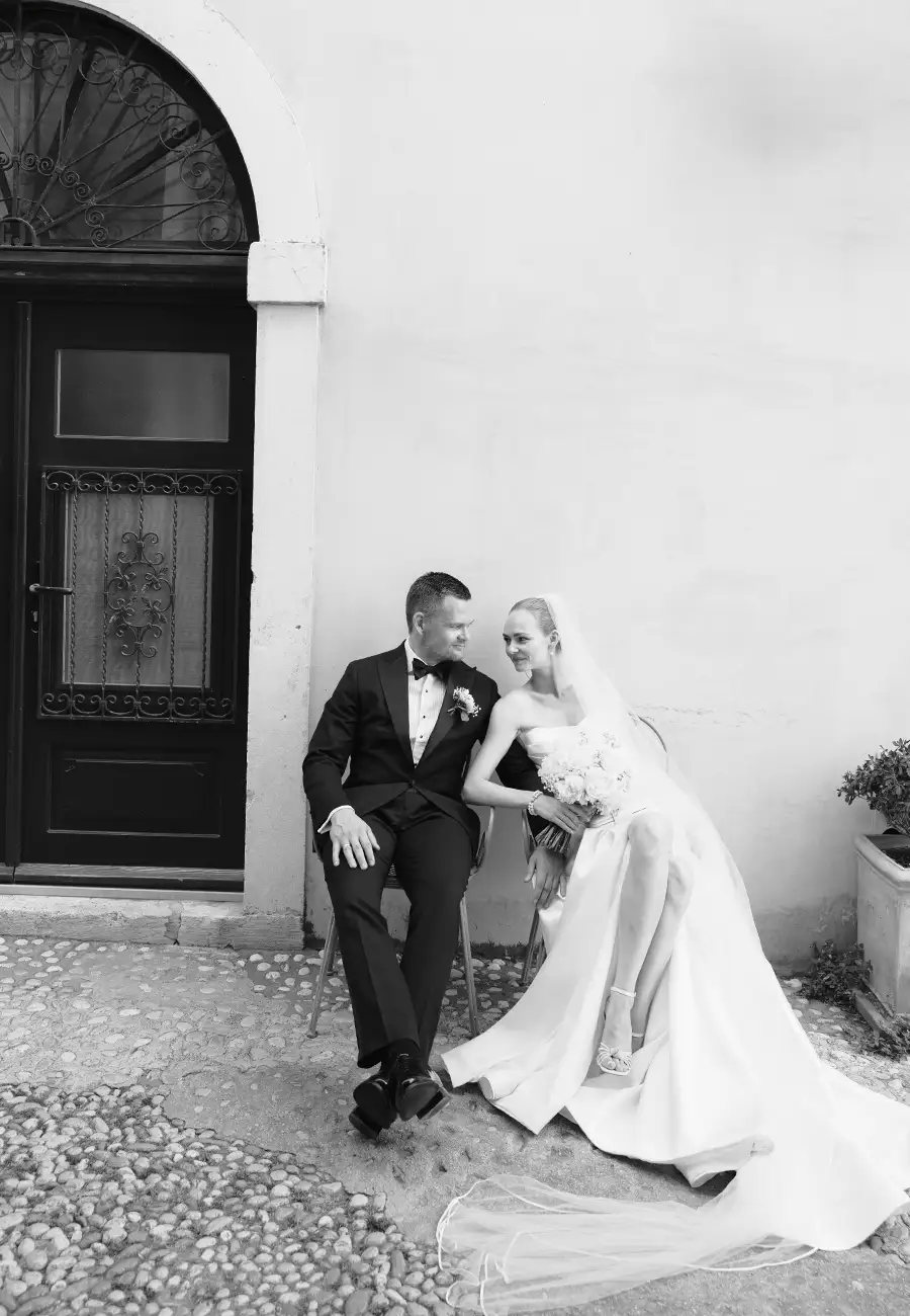 Black and white, Anne and Lars seated, smiling at each other against a stone facade, arched doorway, Dubrovnik