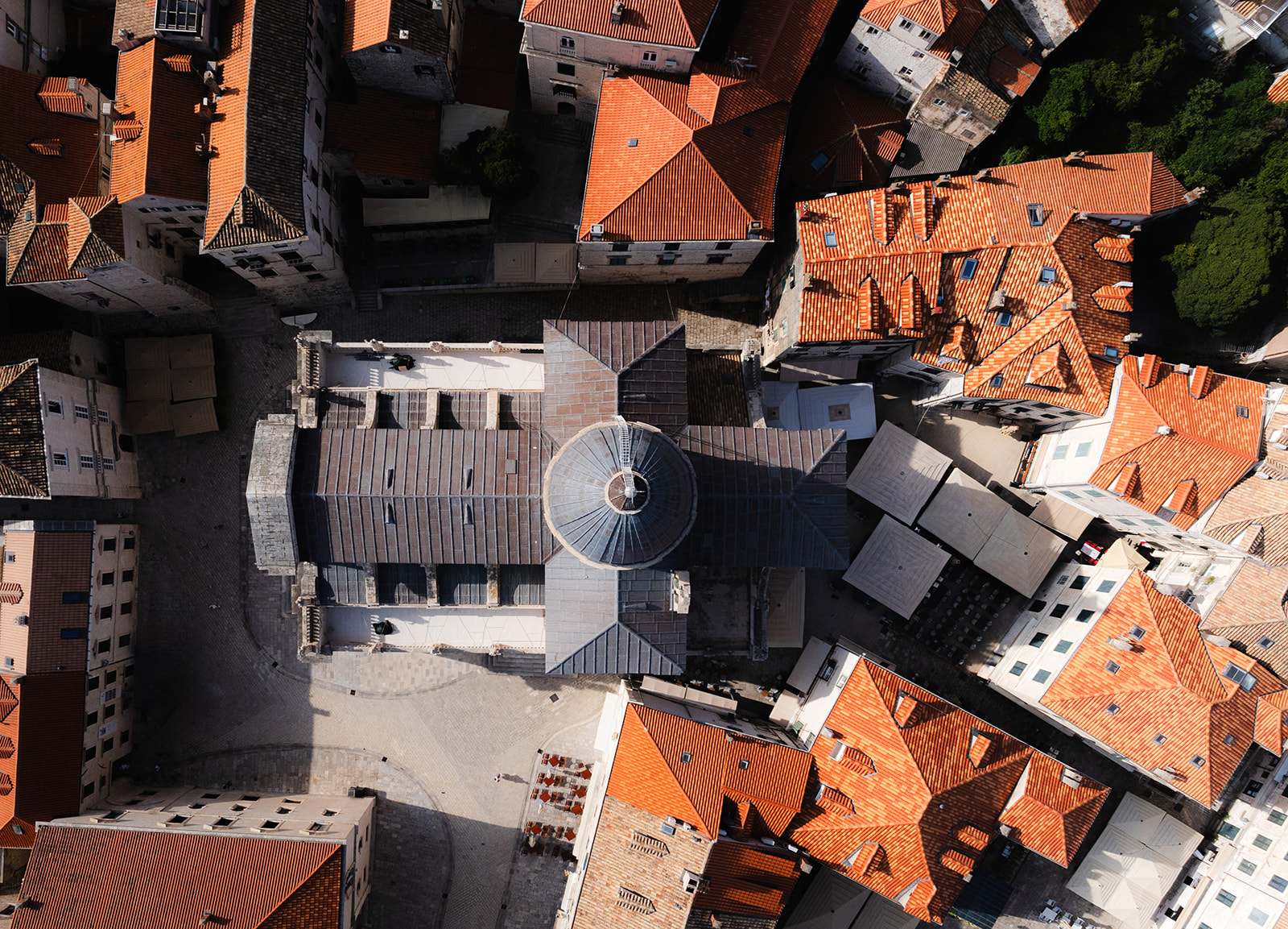Aerial view of a church bell tower and dome surrounded by terracotta-tiled Old Town rooftops