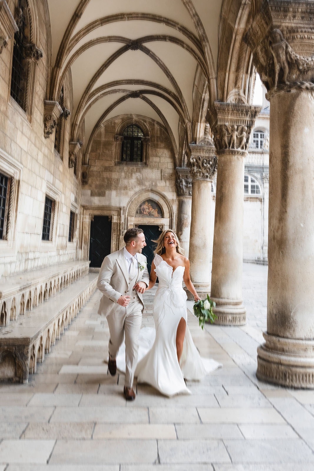 Bride in a Steven Khalil gown and groom walking through the Rector's Palace colonnade, Dubrovnik