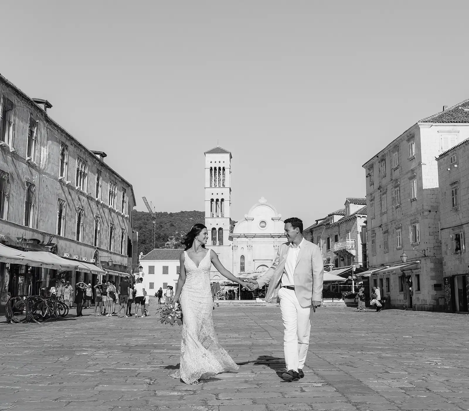 wedding Couple holding hands on Hvar's Pjaca with Cathedral of St Stephen bell tower in background
