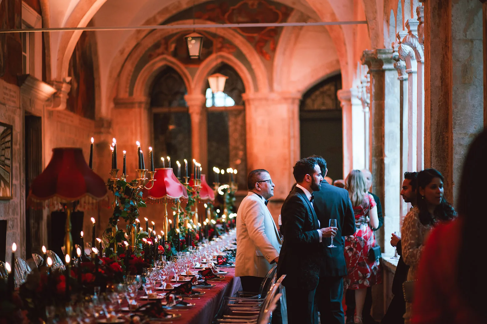Guests mingle with champagne in a candlelit vaulted stone corridor set for the reception.