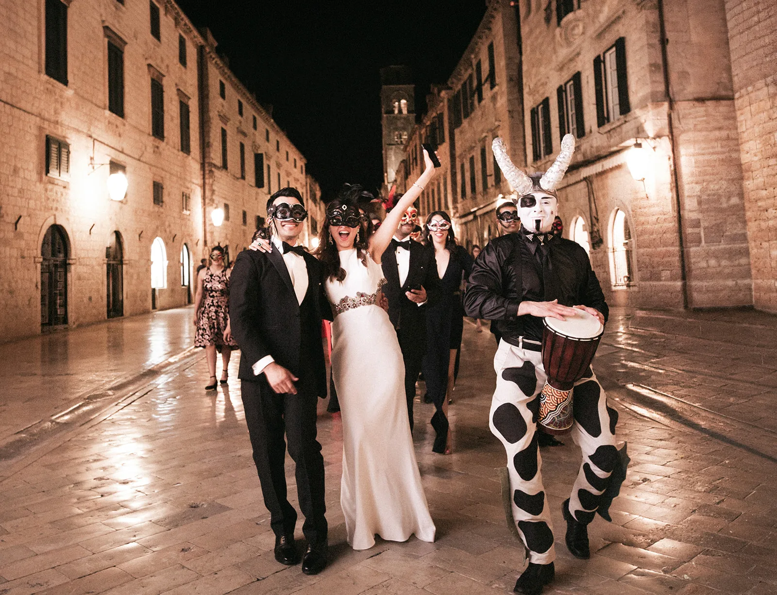 Masked bride and groom lead a costumed night parade down the empty Stradun.