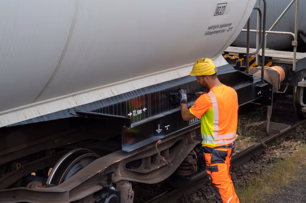 Ein Bahnmitarbeiter bringt einen Temperatursensor an einem Gaswaggon an.
