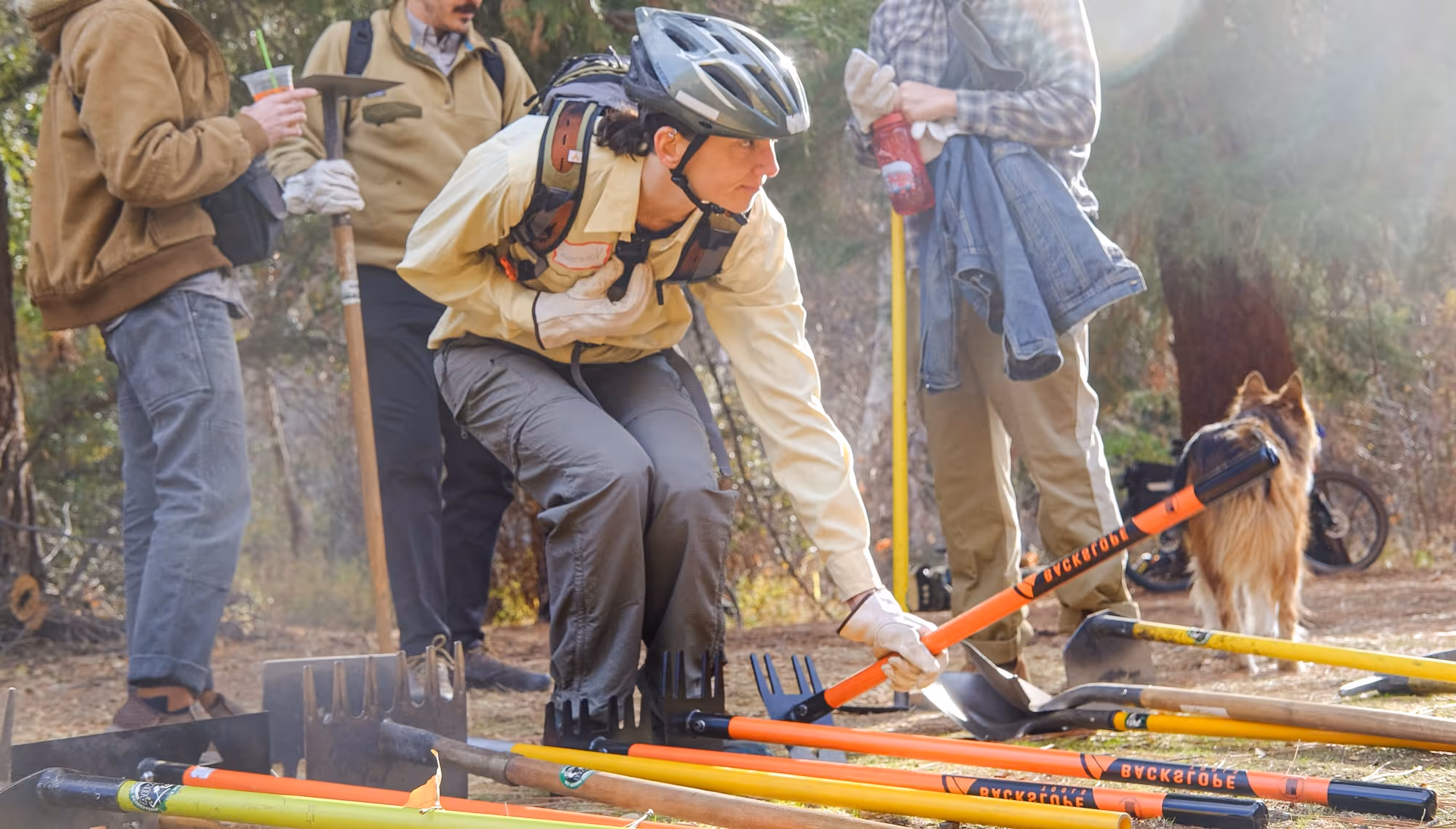 MWBA team member reaching down to pick up a tool for trailwork