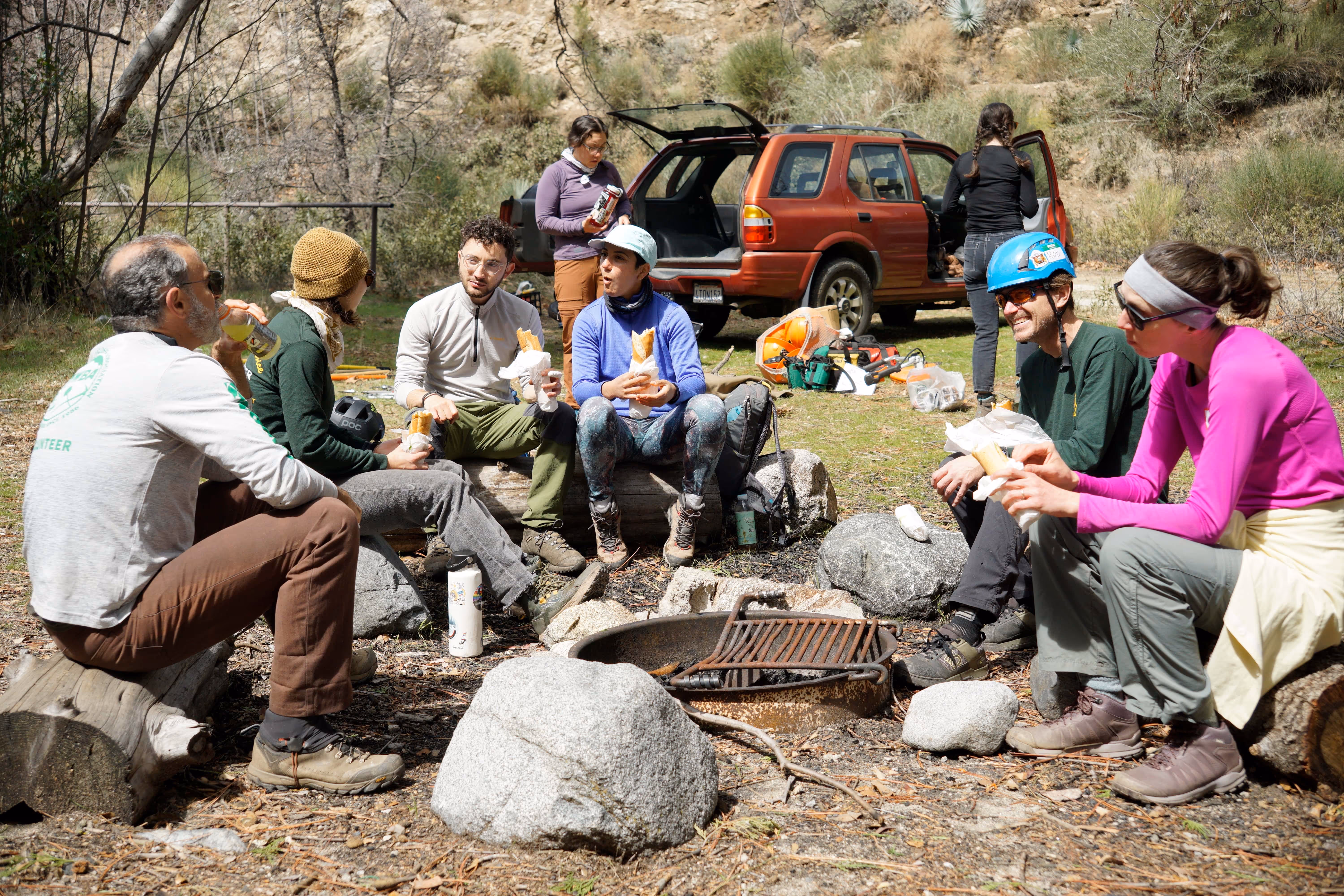 Several MWBA members sitting and eating lunch around an outdoor fireplace
