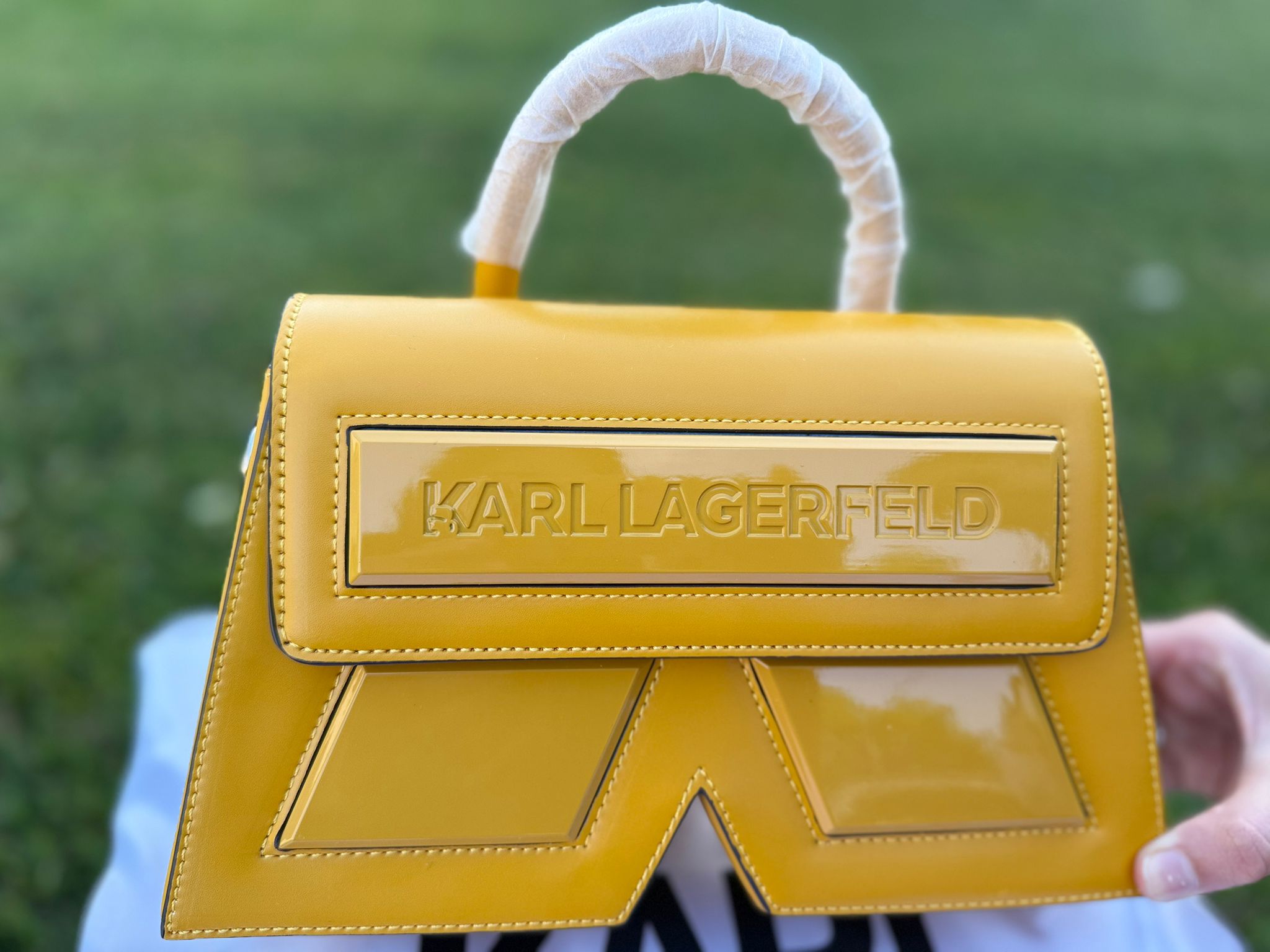 Meet the Karl Signature Structured Mini – where bold geometry meets modern elegance. This glossy mustard yellow handbag makes an unapologetic statement with its sharp architectural shape and the embossed KARL LAGERFELD branding on the front flap. Designed to elevate both casual and occasion wear, it’s compact, edgy, and distinctly fashion-forward.