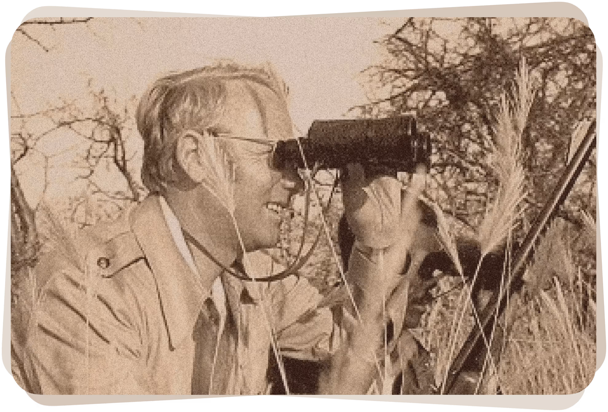 Mann mit Fernglas und Gewehr im Gras beim Beobachten in der Natur.