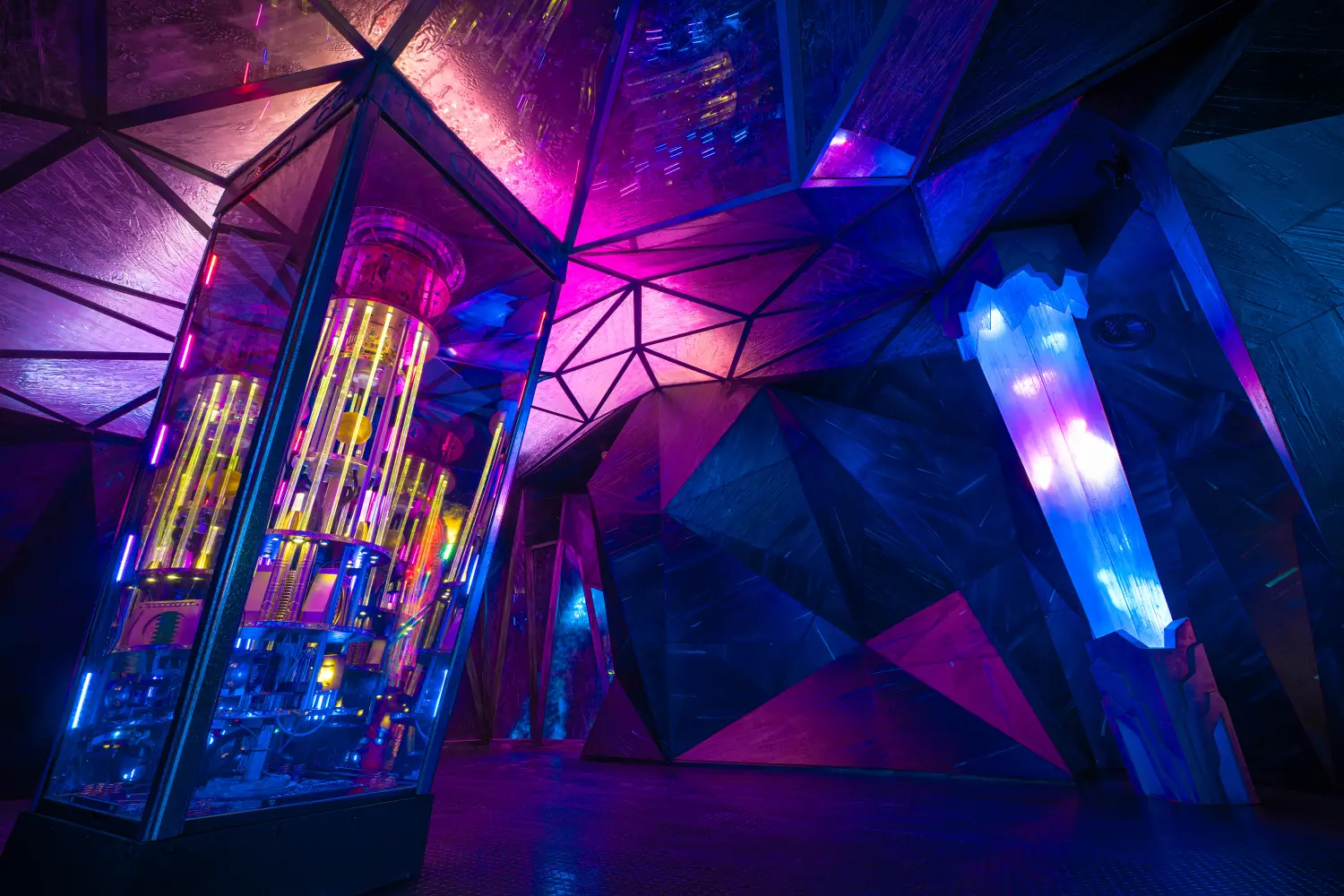Futuristic illuminated room with glowing geometric shapes and crystal-like structures in vibrant pink, purple, and blue lights.