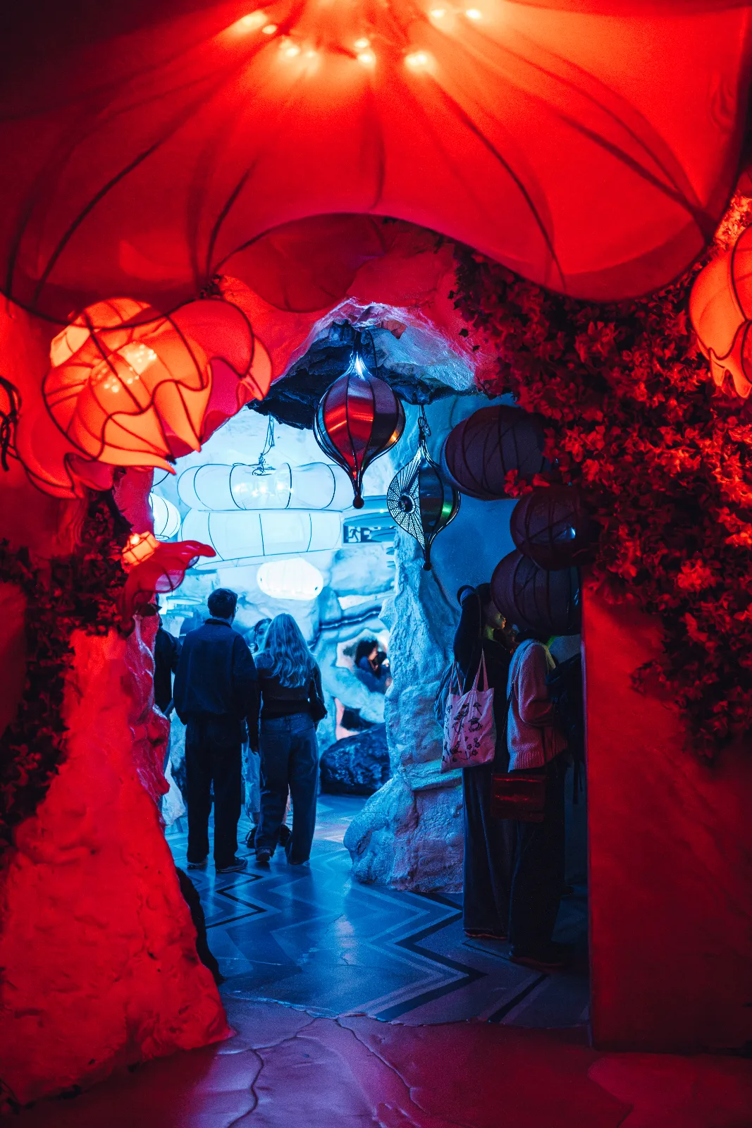 Family walking through arch with vibant red flowers in immersive experience.