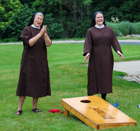 A sister and a postulant playing a game outside