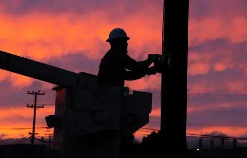 Lineman at the sunset working on the pole and installation gridscope