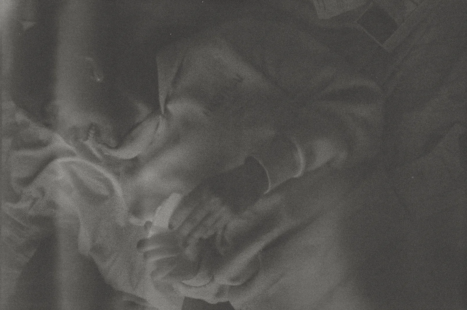 Black and white photo of a person with curly hair sitting down, holding and looking at a small object in their hands.