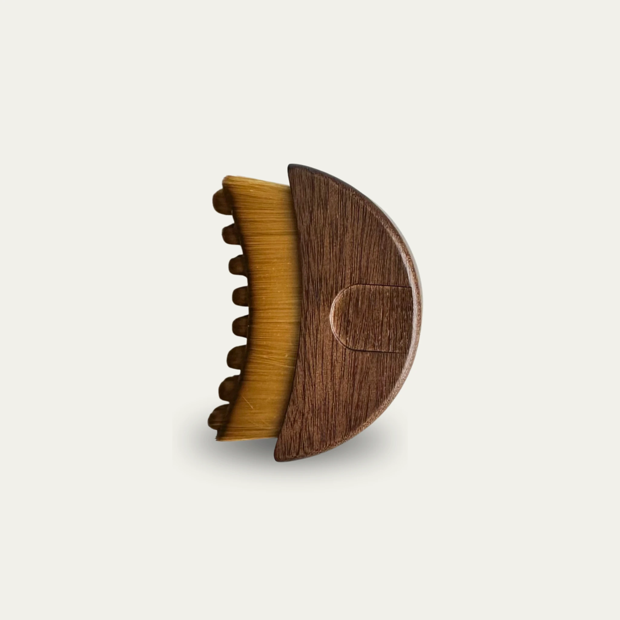 Small round wooden brush with light brown bristles and a thumb rest on the handle.