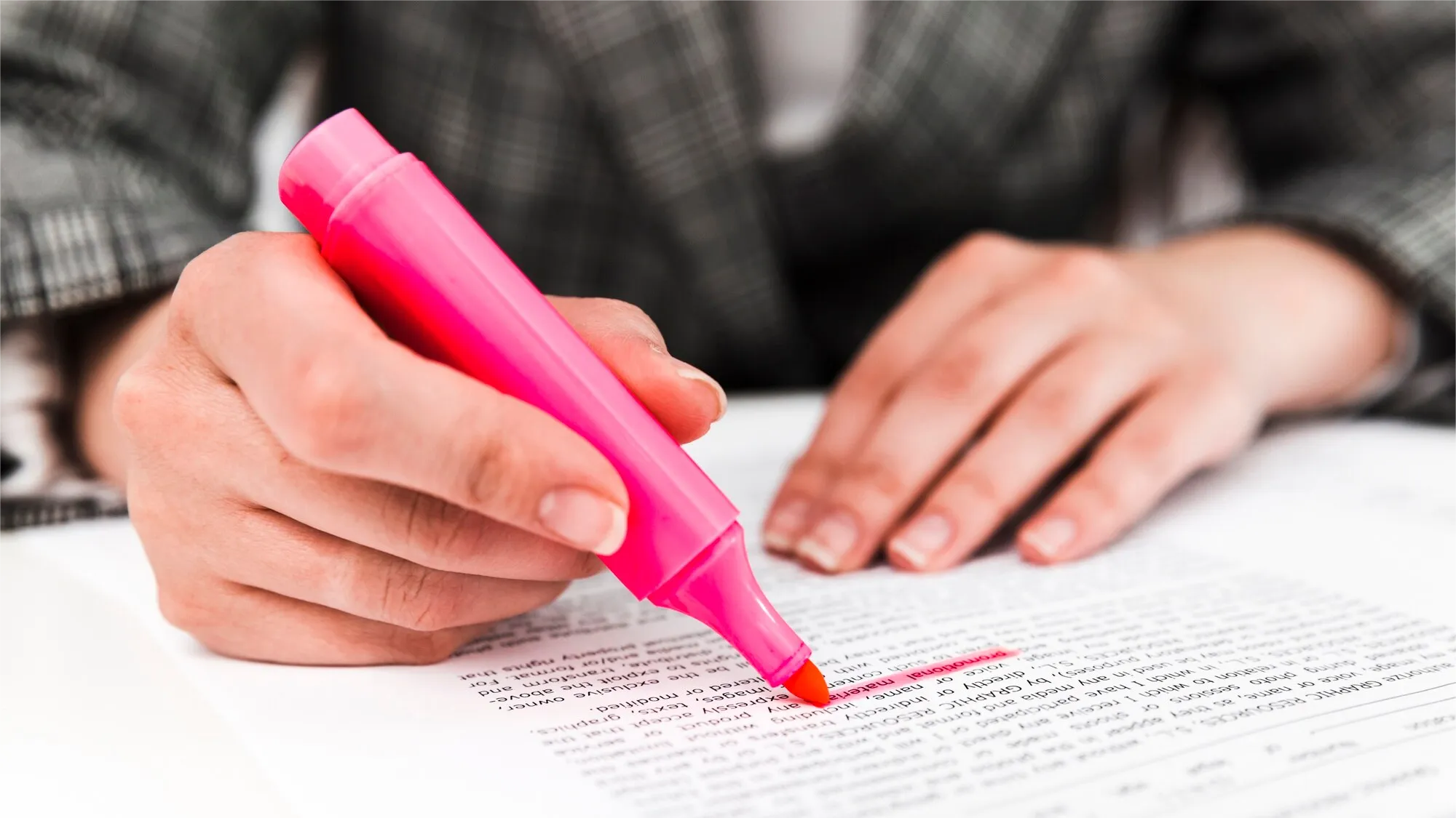 A person highlights a printed document using a bright pink highlighter. This close-up image suggests manual processes that could benefit from digitization, reinforcing the value of retail communication solutions and cloud-based tools for small business operations.