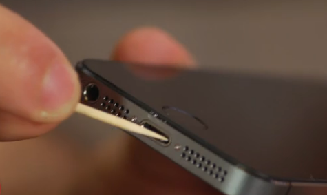 iPhone with a toothpick being used to clean out the charging port