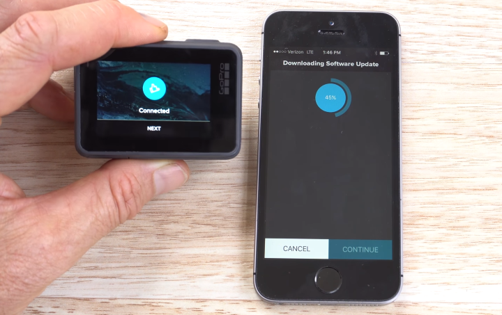 GoPro HERO6 displaying a successful connection screen, and a smartphone in the process of downloading an update.