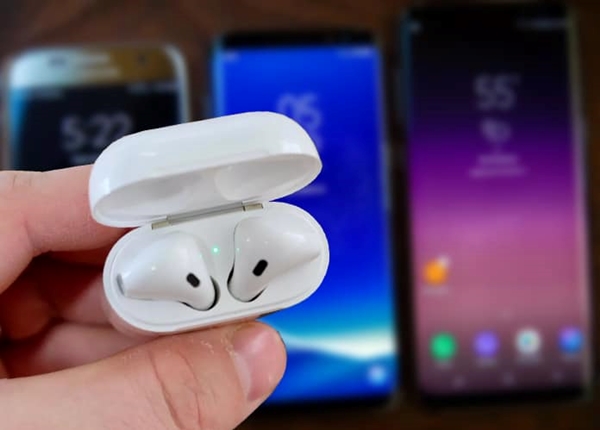 Apple AirPods case with the lid open displaying an illuminated white light.