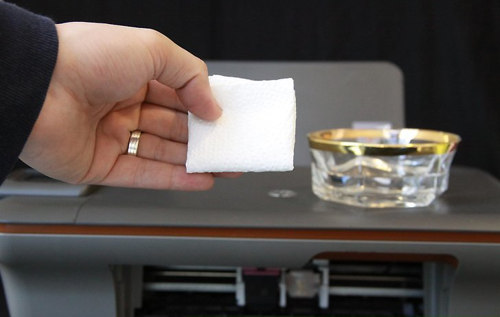 Photo of an individual preparing a cloth to clean their printer with.