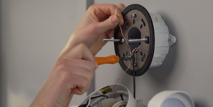 Connecting copper ground wire to green ground screw.