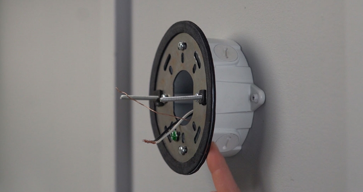 Camera mounting bracket installed on junction box with wires pulled through middle.