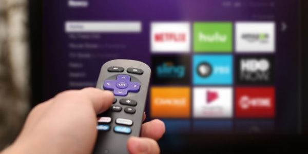 Roku remote pointed at TV screen.