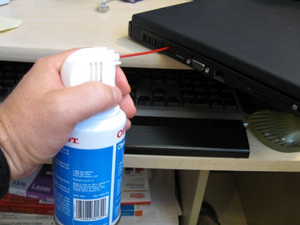 Using gas duster to clean laptop vents.