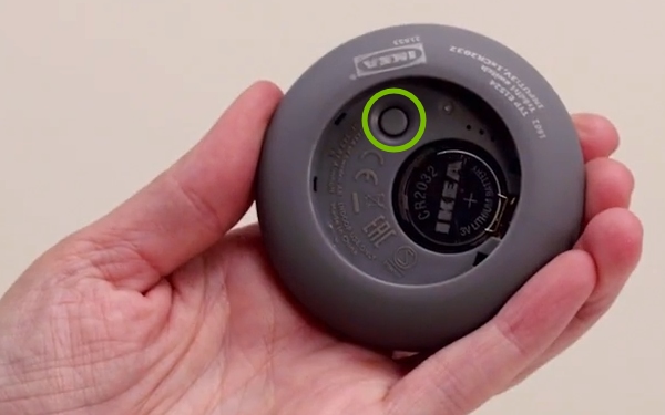 Button highlighted in battery compartment of IKEA Tradfri remote control.