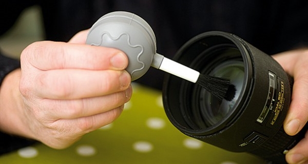 Cleaning lens with blower and brush.