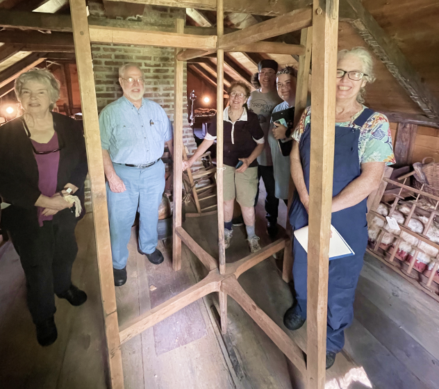 A group of participants standing around a frame during the textiles workshop.