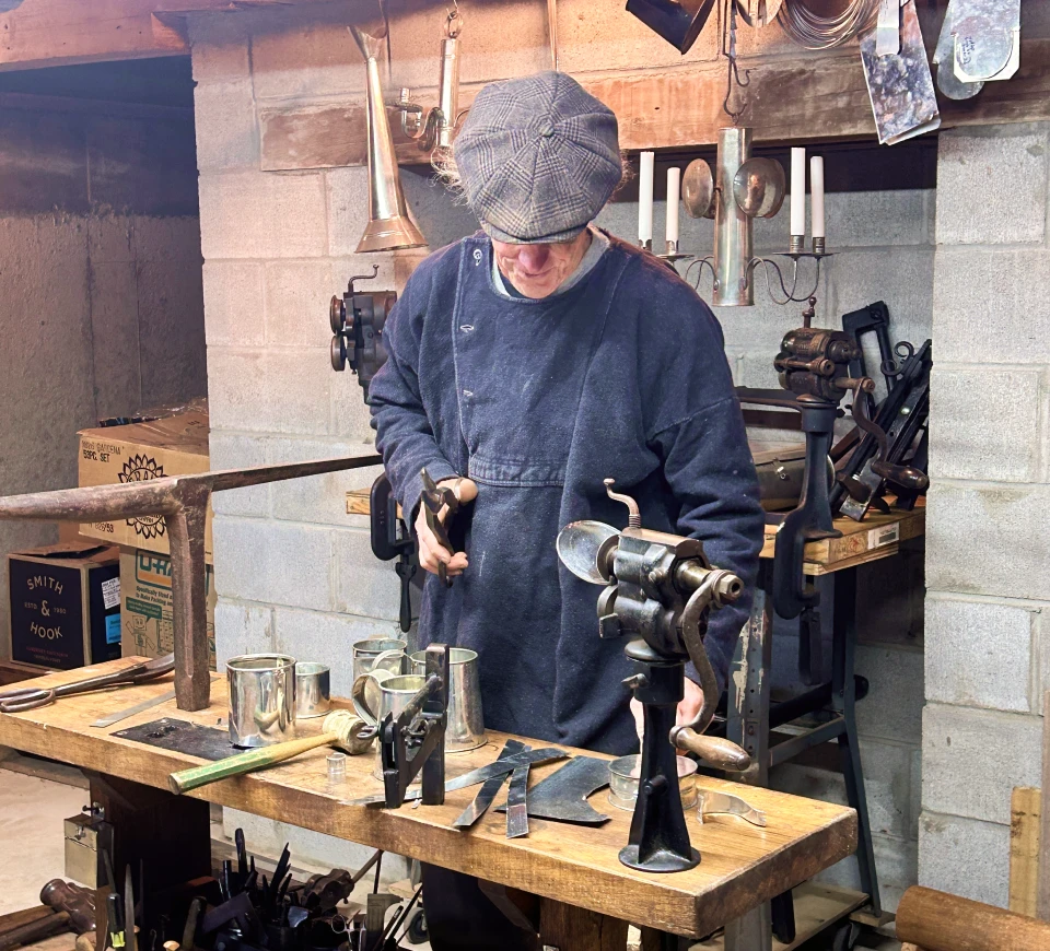 An image of a tradesman working at the tinsmithing station at Kilts Farm.