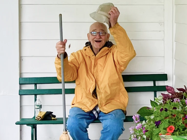 A man sitting on a bench outside at Kilts Farm saluting to the photographer.