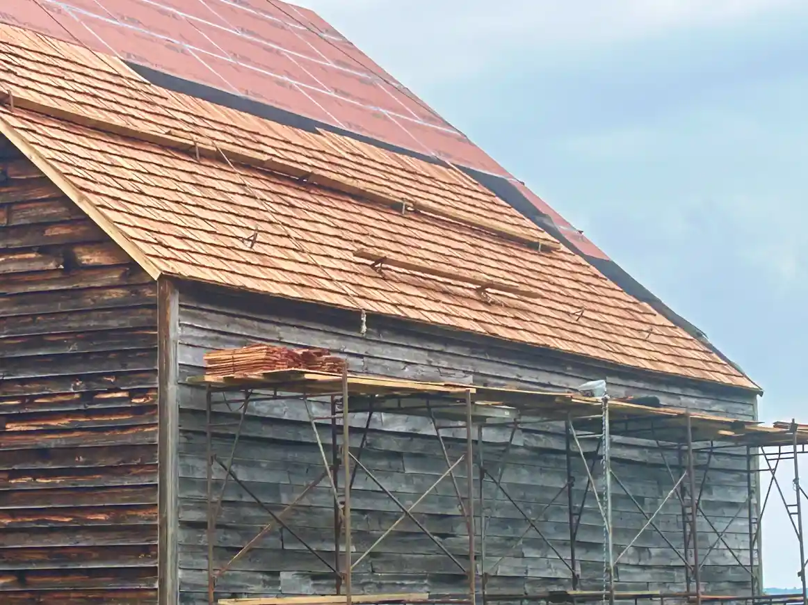 Close up view of the dutch barn roof replacement with wooden shingles.