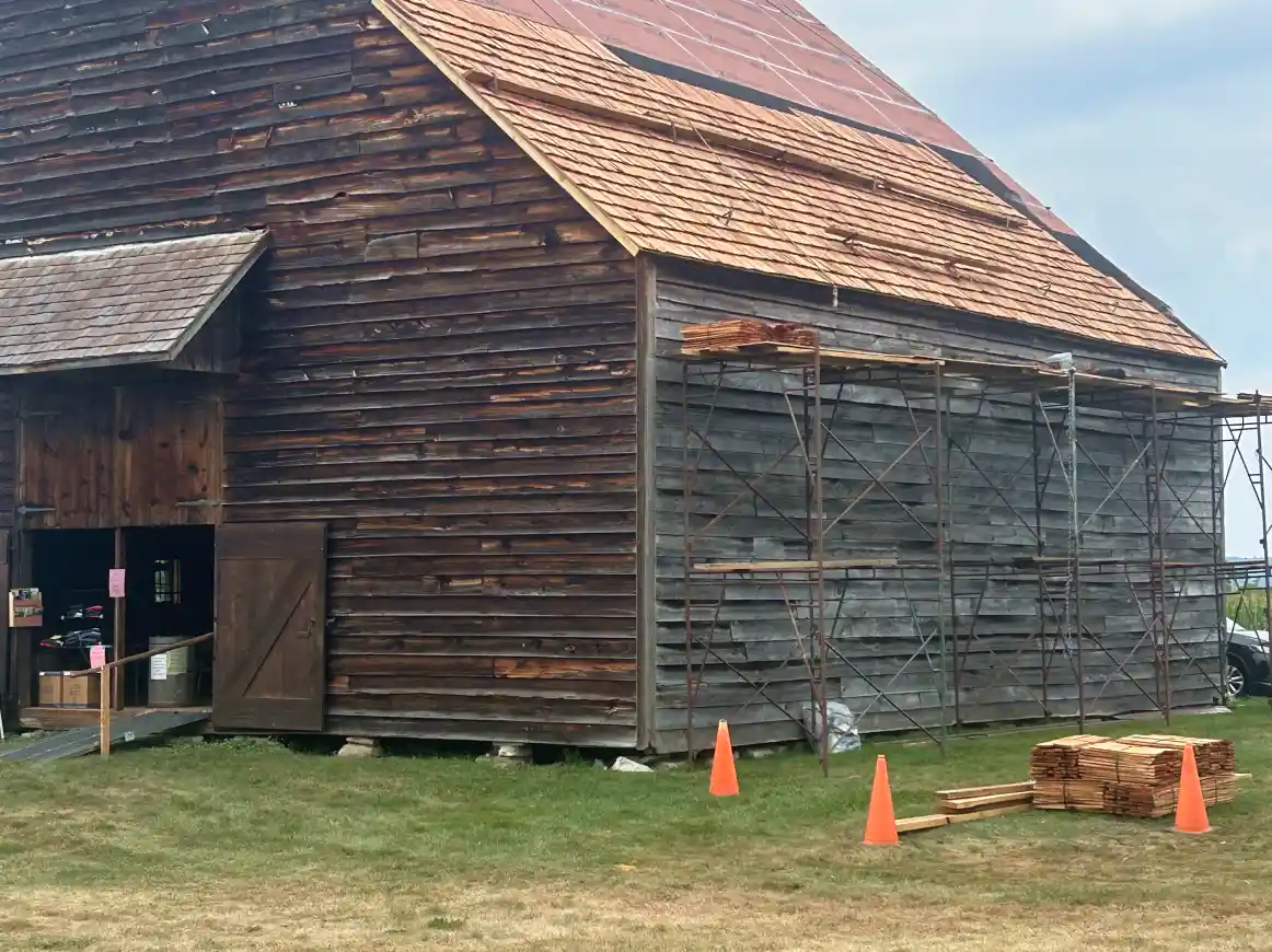 Distant view of the dutch barn roof replacement with wooden shingles.