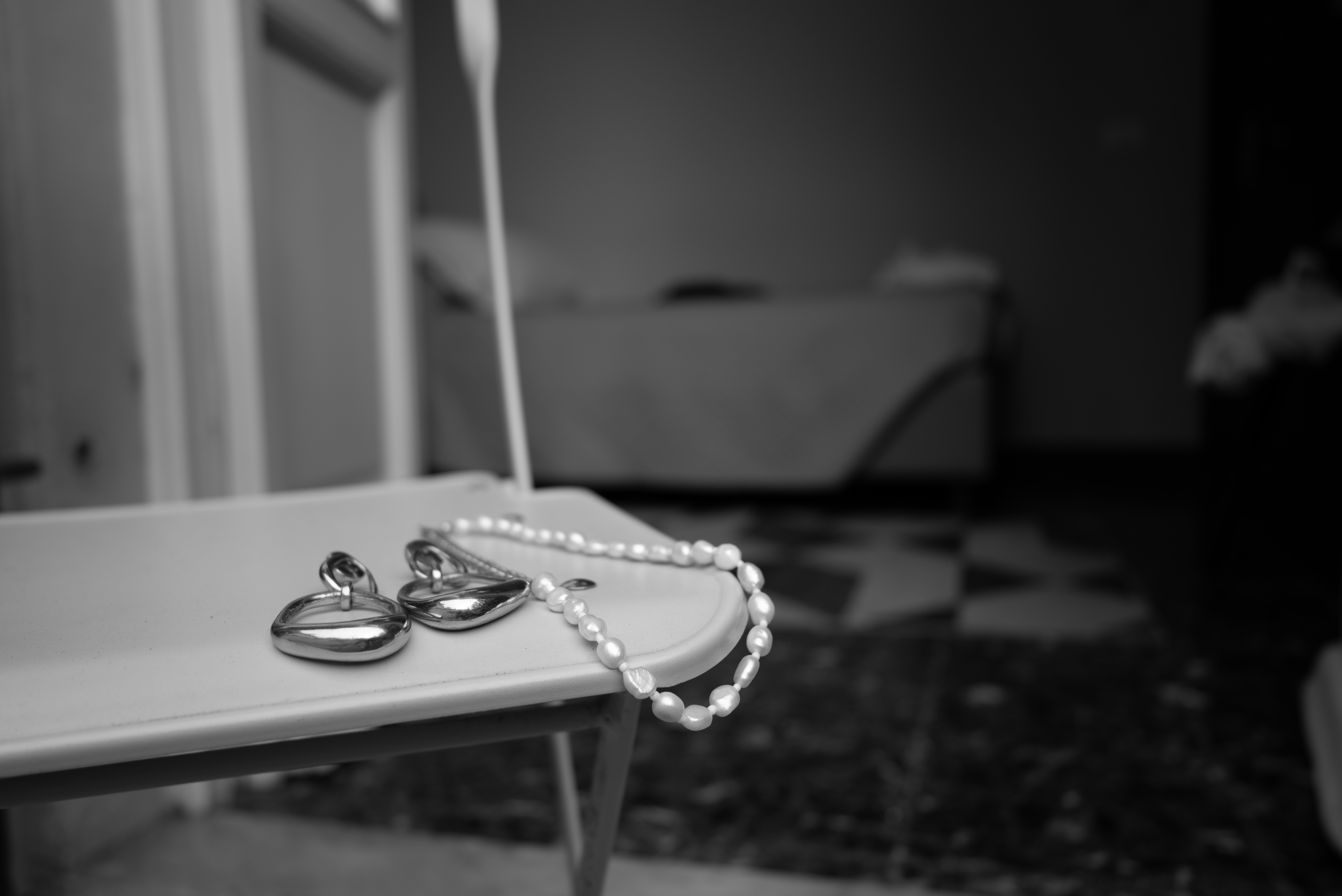 Black and White image: Earrings and necklace on chair 