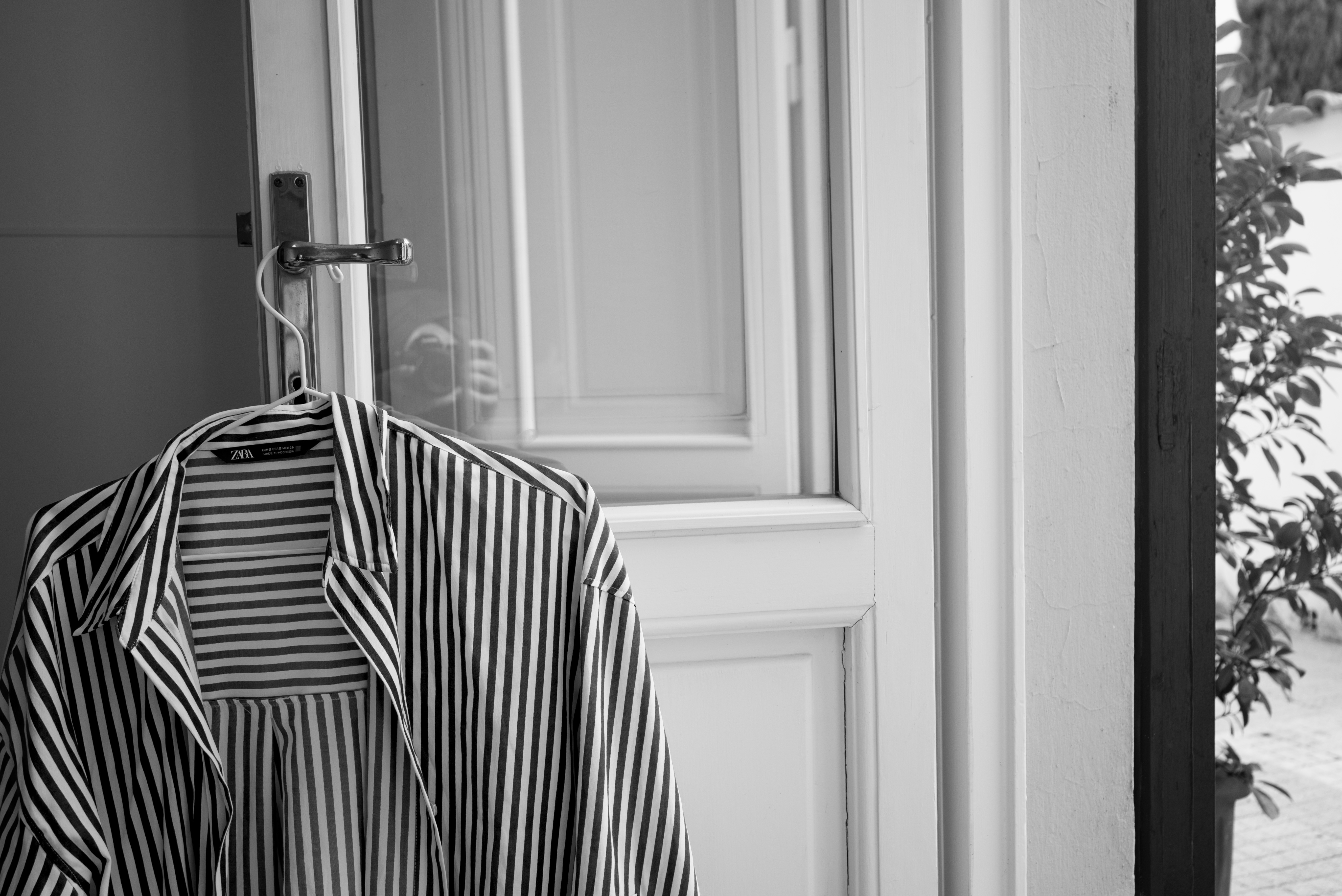 Black and White image: Shirt hanging on back of door