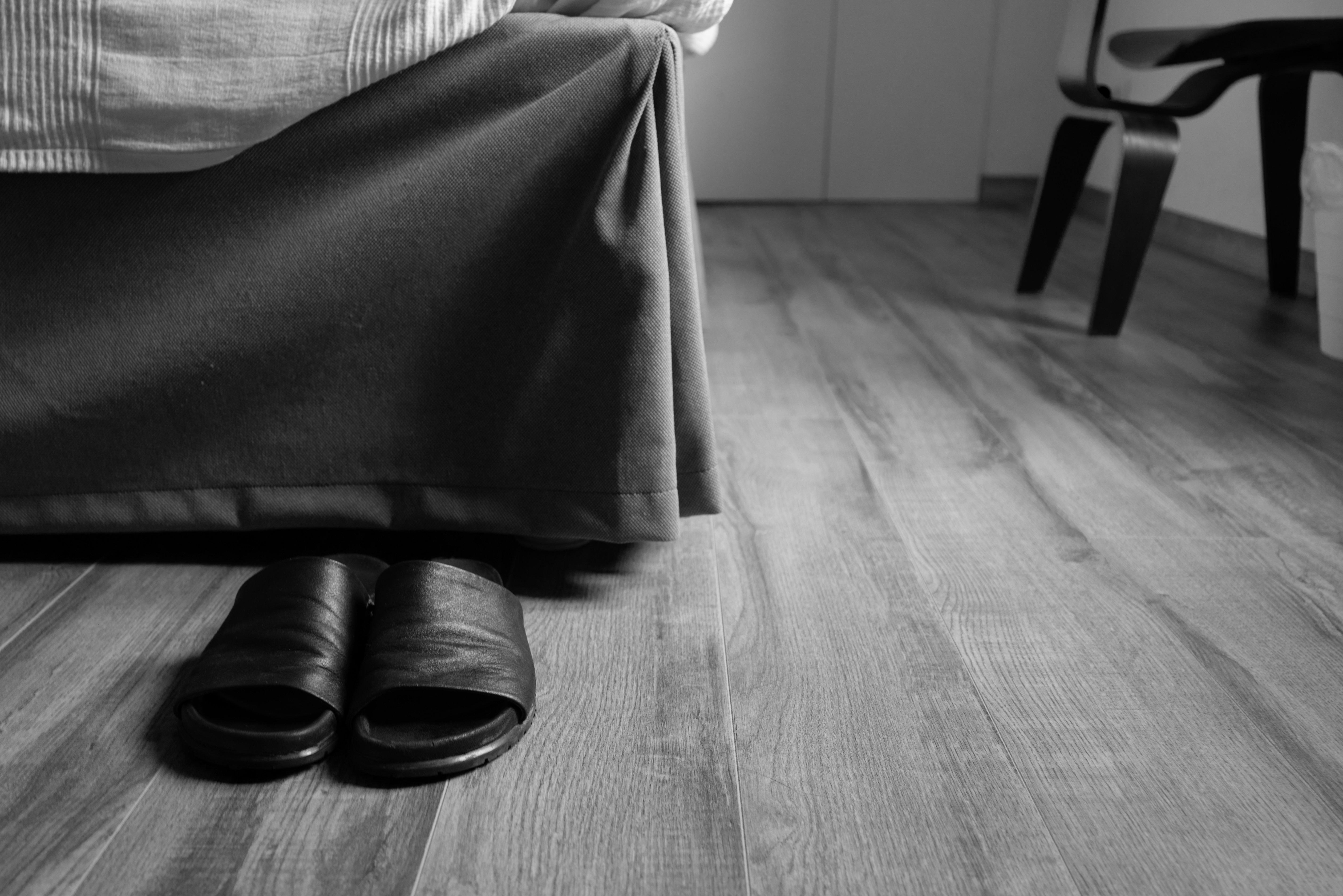 Black and White image: Sandals at end of bed 