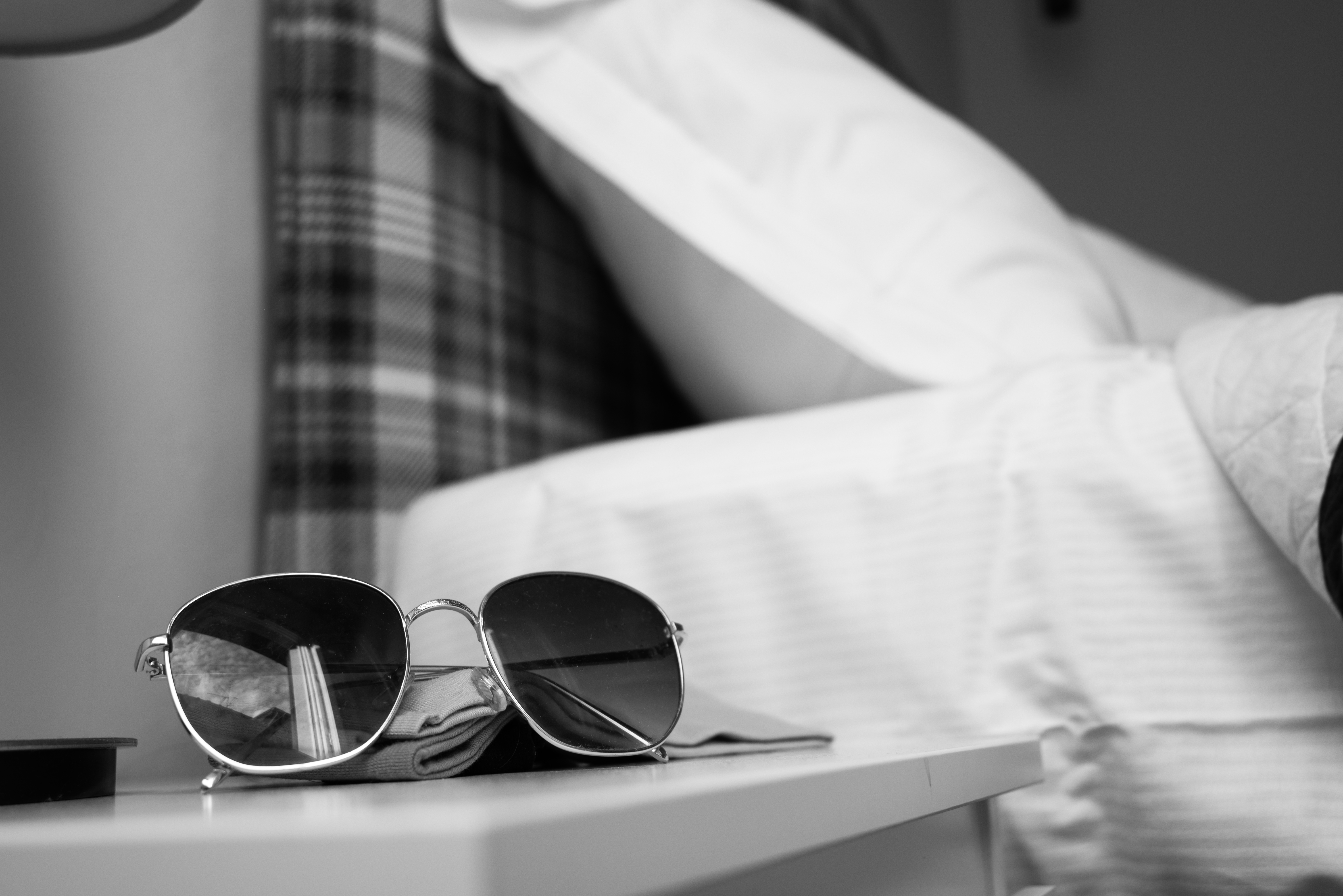 Black and White image: Sunglasses on bedside table