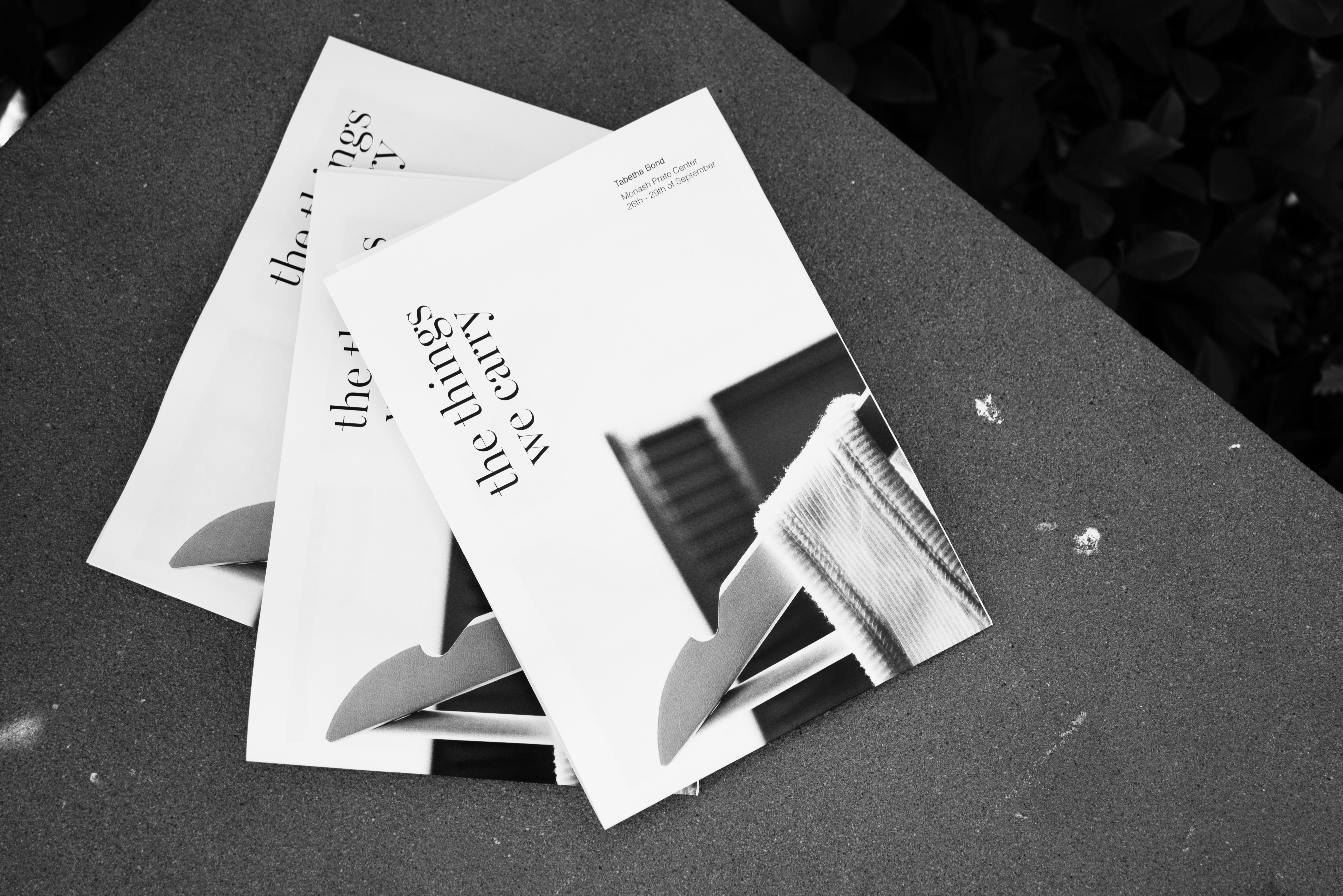 Black and White image: three brochures on concrete bench