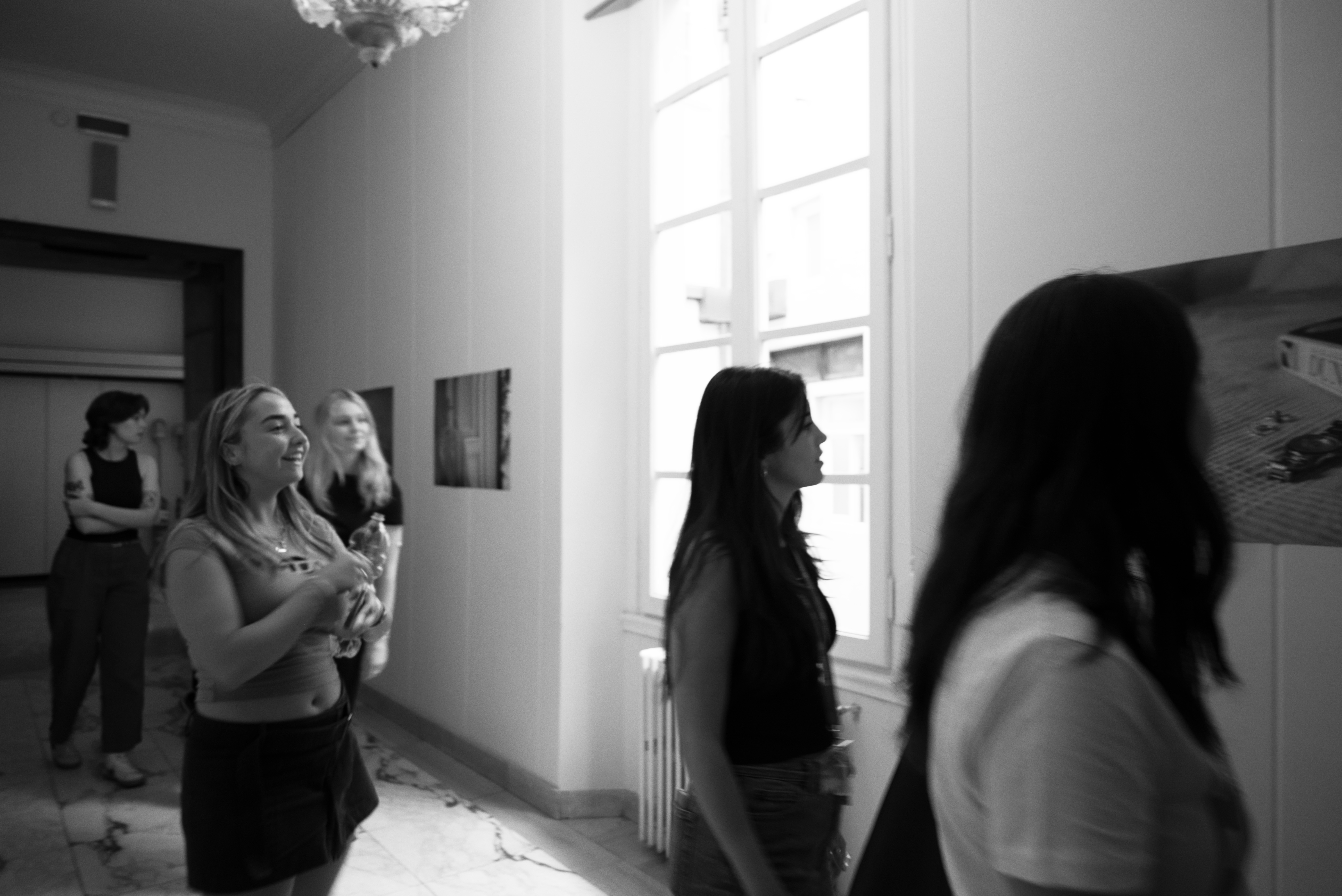 Black and White image: Hallway with photographs and people 